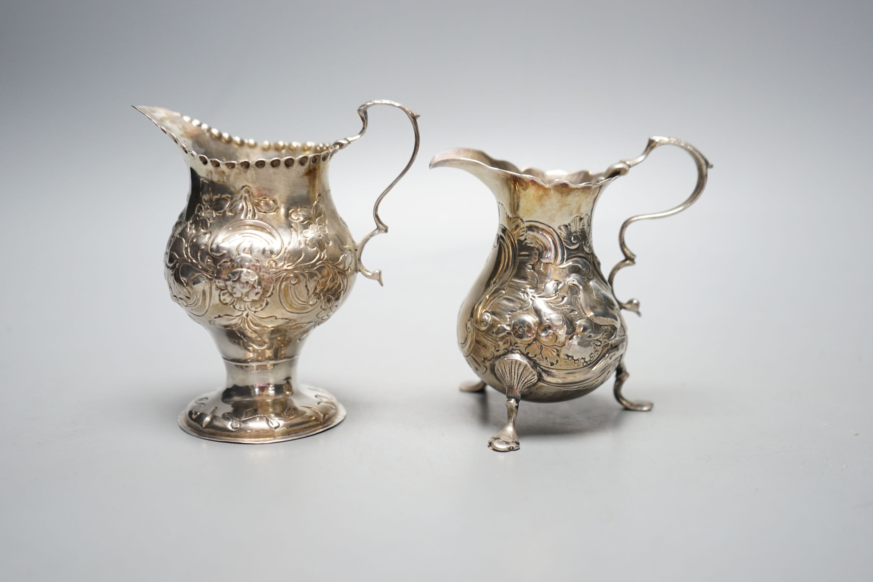 Two 18th century silver cream jugs, with later embossed decoration, London, 1753 & London, 1770, tallest 10.6cm, 174 grams.